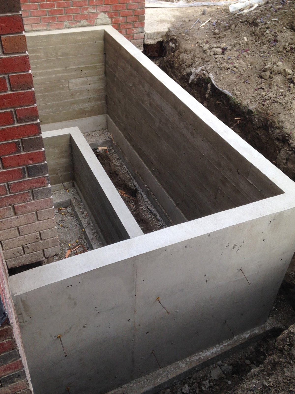Finished poured concrete walls beside a brick house